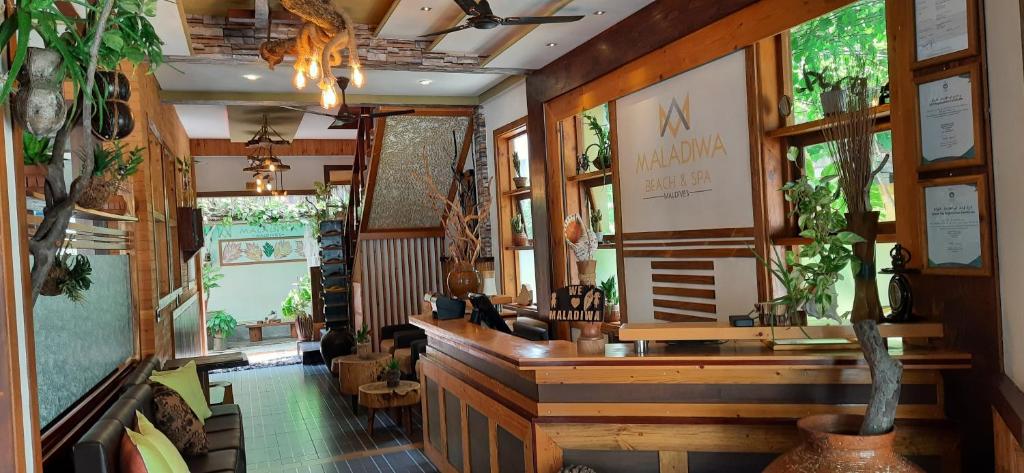 Lobby at Maladiwa Beach & Spa with a wooden reception desk, plants, and lounge seating? area