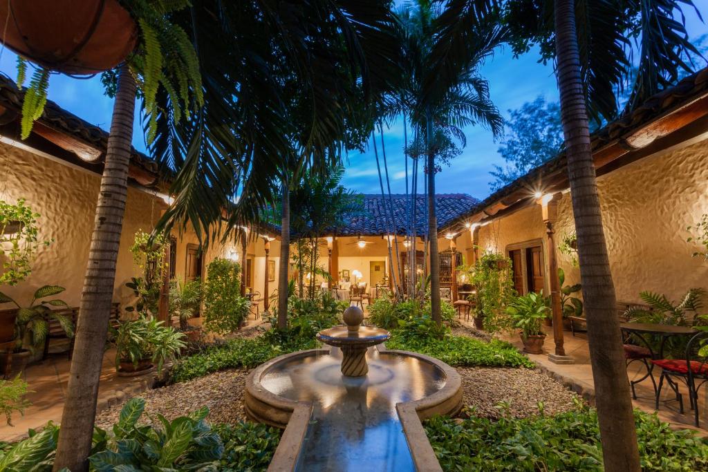 Courtyard with a central fountain, surrounding plants, and warm lights in a rustic villa courtyard at dusk.