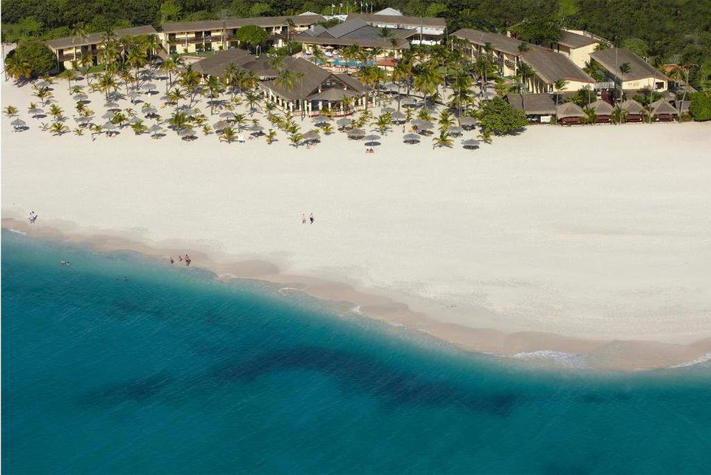 Aerial view of a tropical beach resort with white sand, palm trees, and turquoise ocean.