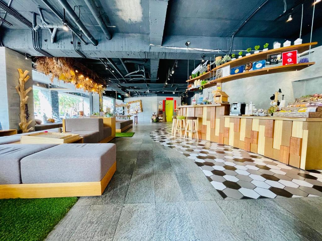 Open-plan cafe interior with a long wooden bar on the right, hex tile floor, and gray cushioned seating on the left.