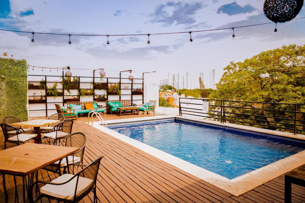 Rooftop pool with wooden deck, lounge seating, and string lights against a city skyline.