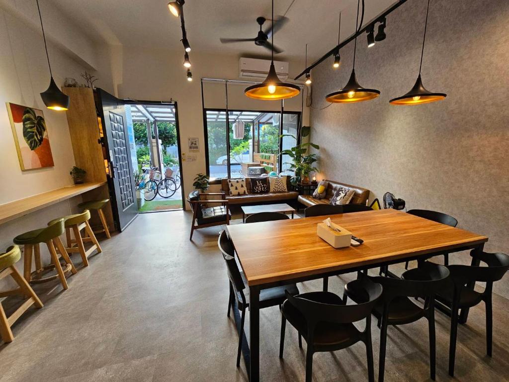 Cozy cafe interior with a long wooden communal table, black chairs, and warm pendant lighting.