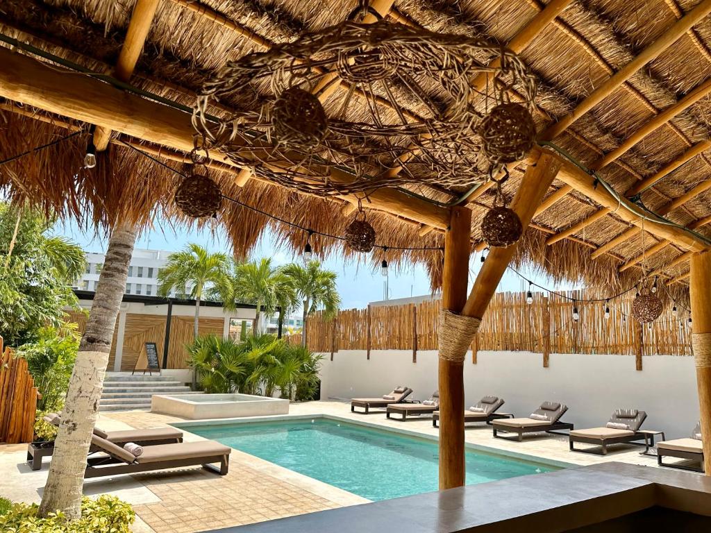 Poolside cabana with a thatched roof, wooden posts, and string lights; lounge chairs surround a rectangular pool.
