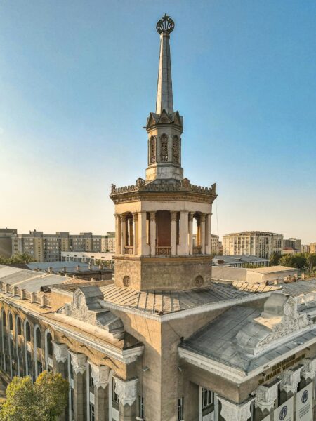 Tall decorative spire with a crown top rising from a historic rooftop against a clear blue sky.