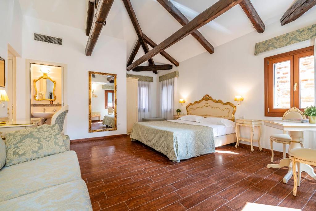 Luxurious hotel bedroom with a carved gold headboard, pale teal bedspread, and exposed dark wooden beams over a polished wood floor.