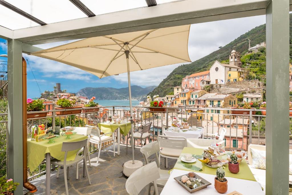 Terrace cafe with a large umbrella, set tables, and a coastal hillside town in the background.