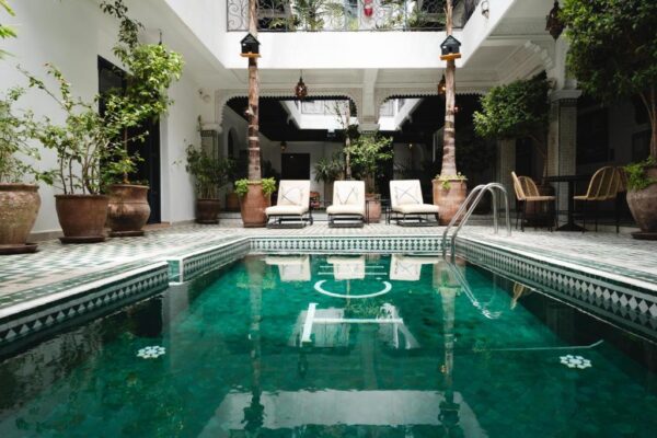 Indoor courtyard pool with white arches, potted plants, and lounge chairs surrounding the water
