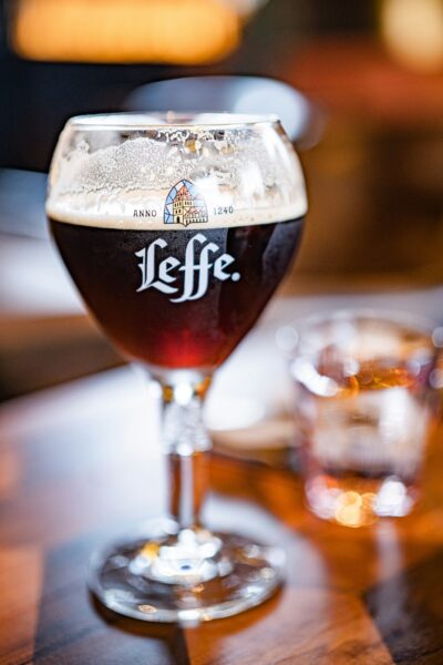 Leffe beer in a tulip glass with a foamy head on a wooden table, logo visible on the glass