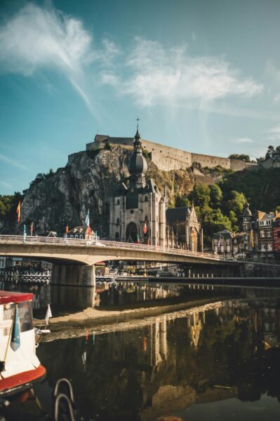 Historic church with a bulbous dome on a rocky hillside, overlooking a bridge and river in a quaint town.