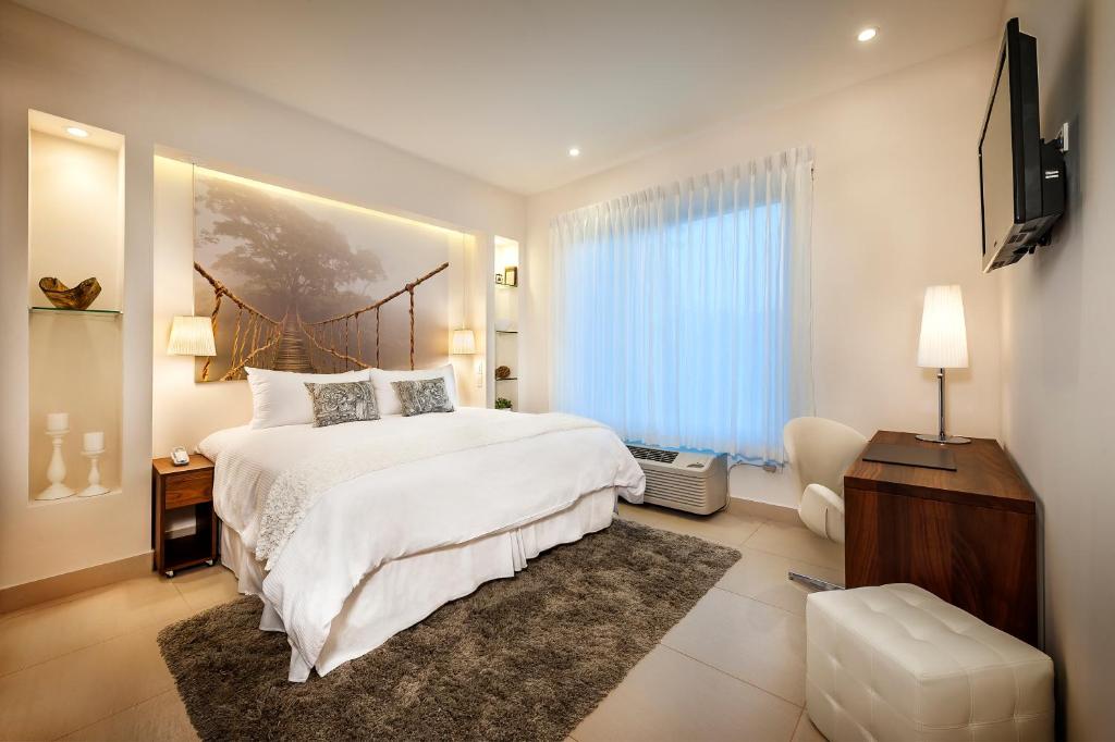 Bright hotel bedroom with a king bed, rope-bridge mural headboard, and warm bedside lamps.