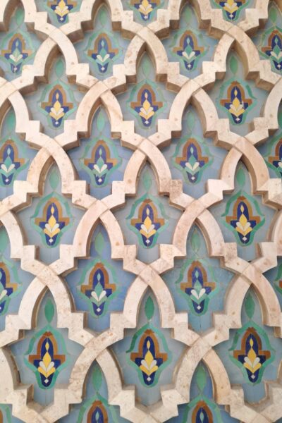 Patterned wall mosaic of interlocking arches with pastel blue, green, beige and yellow floral motifs.
