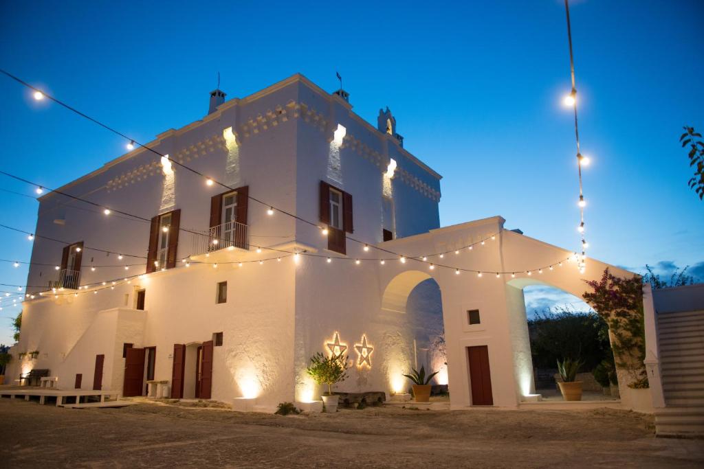 White two-story building at dusk with string lights, arched entrance, and star-shaped lights on the wall.