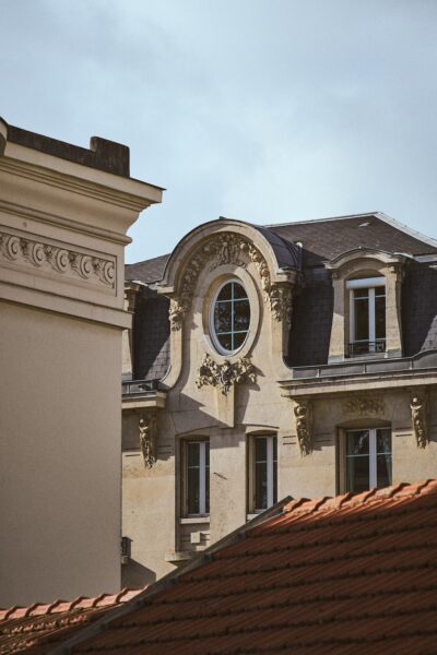 Ornate historic building facade with a round window and decorative stone carvings, under a blue sky.