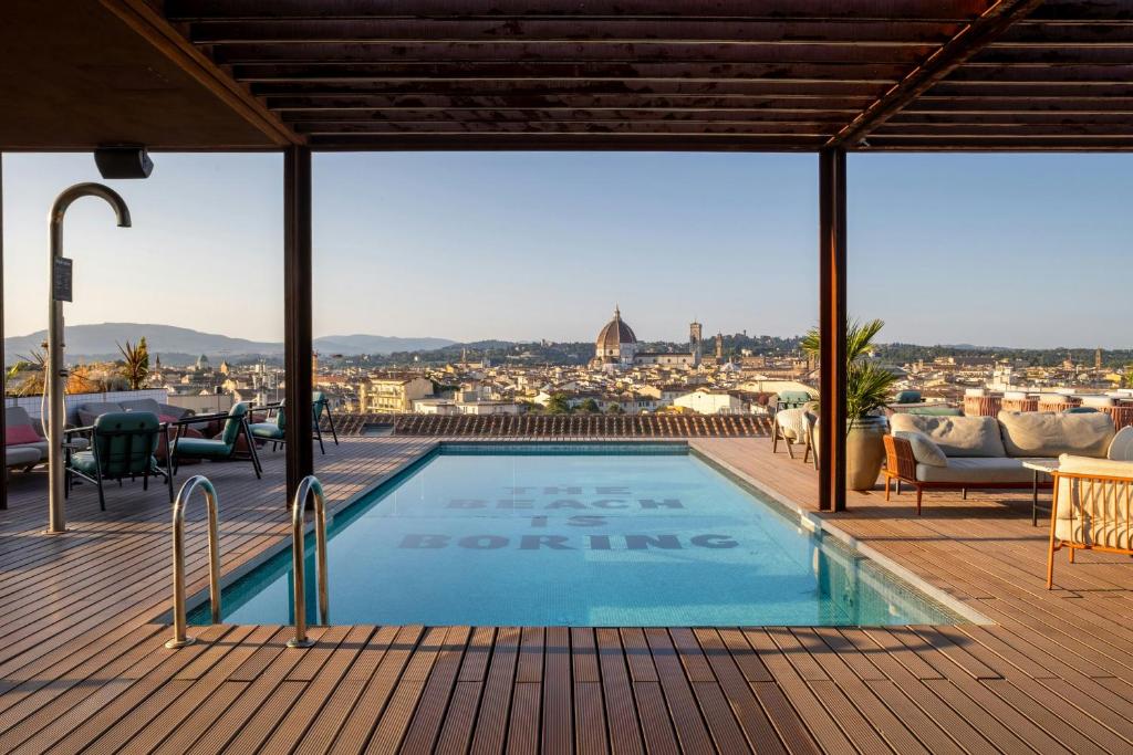 Rooftop pool on a wooden deck with outdoor seating, overlooking Florence with the Duomo in the distance.